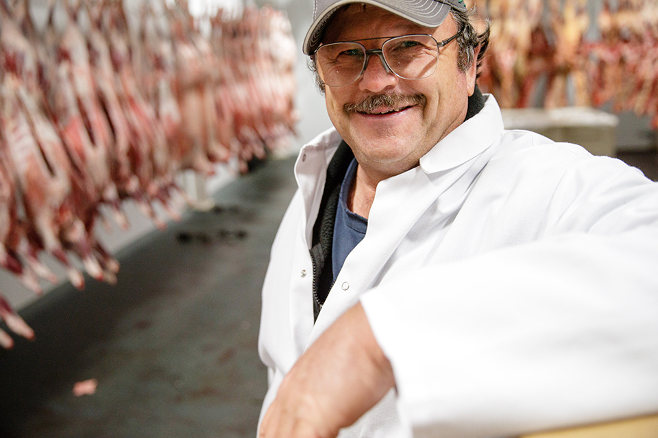 Reed Anderson with lamb in the farm's processing facility cooler. Anderson's operation is a closed loop. Photo by Rob Kerr